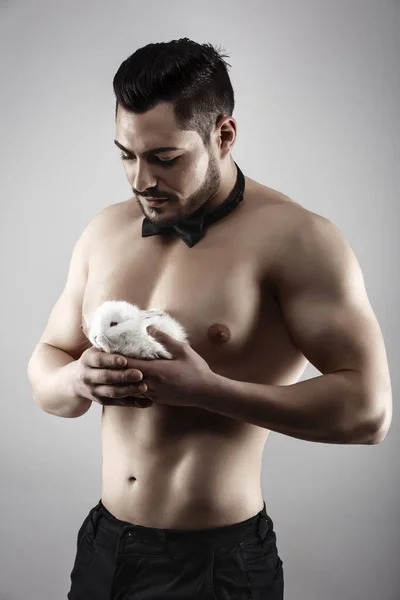 Ein muskulöser Mann mit einem Kaninchen in der Hand — Stockfoto