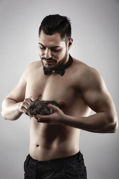 Ein muskulöser Mann mit einem Kaninchen in der Hand — Stockfoto