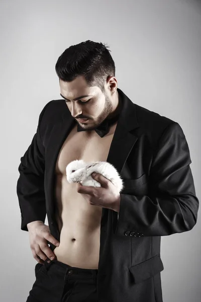 A muscular man with a rabbit in his hand — Stock Photo, Image