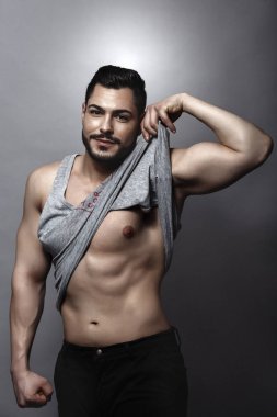 Yakışıklı kaslı adam stüdyoda poz veriyor.