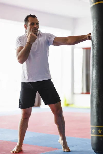Kickbox lutador formação em um ginásio com sacos de soco, ver o todo — Fotografia de Stock