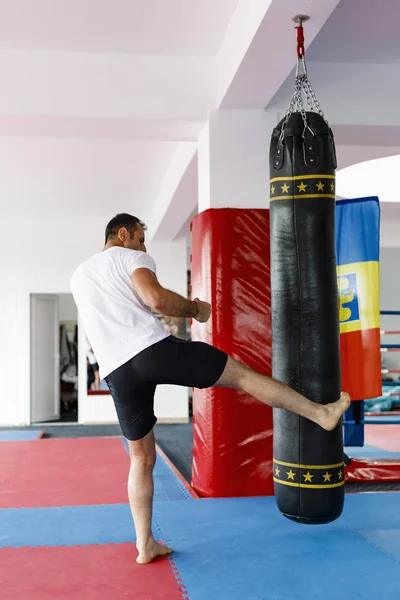 Kickbox combattant entraînement dans une salle de gym avec des sacs de boxe, voir l'ensemble — Photo