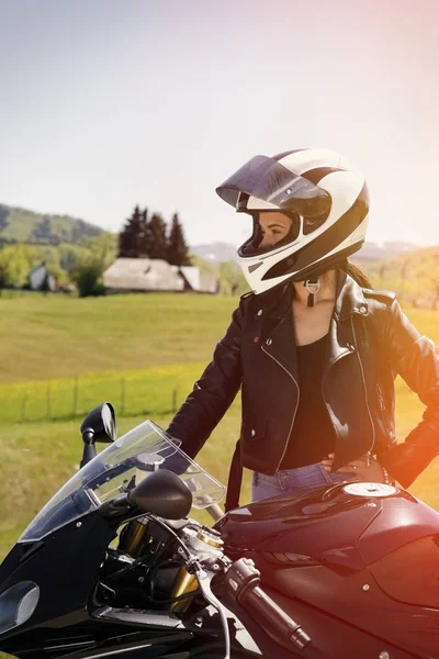 Beautiful woman posing with a motorcycle in mountain scenery