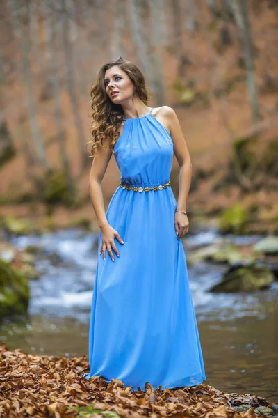 Kvinna i blå klänning nära en flod på höstdagen — Stockfoto