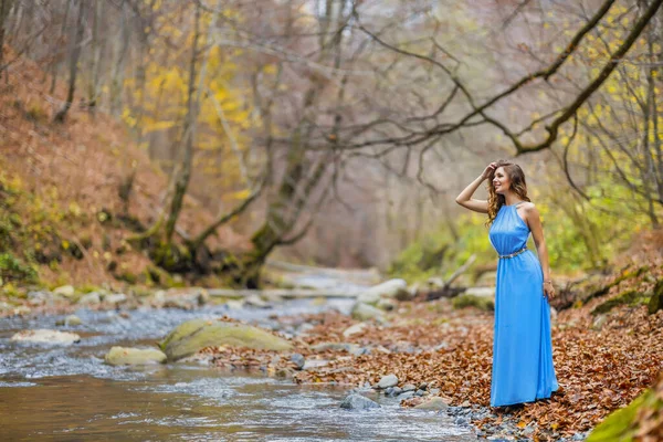 Mulher em vestido azul perto de um rio no dia de outono — Fotografia de Stock