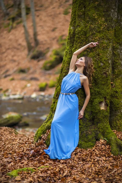 Piękna kobieta w niebieskiej sukience w lesie jesienią — Zdjęcie stockowe