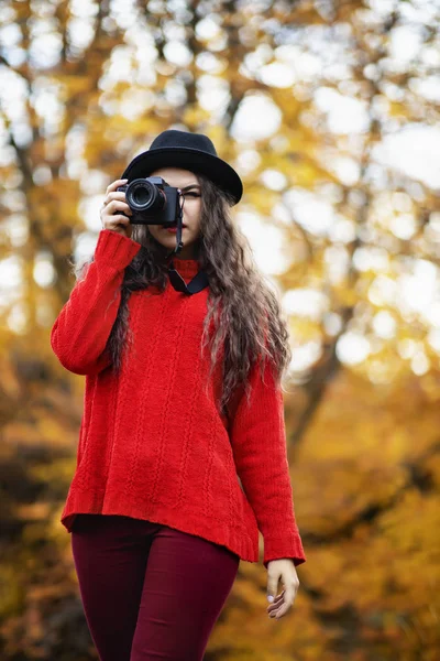 Schöne junge Frau mit moderner Fotokamera im Herbstpark — Stockfoto