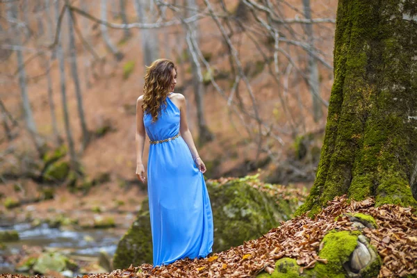 Beautiful woman in blue dress in the forest in autumn day — Stock Photo, Image