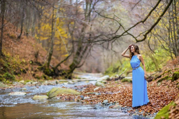 Mulher em vestido azul perto de um rio no dia de outono — Fotografia de Stock