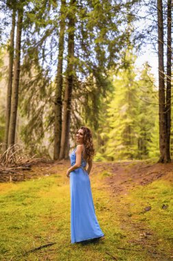 Sonbahar günü ormanda mavi elbiseli güzel bir kadın.