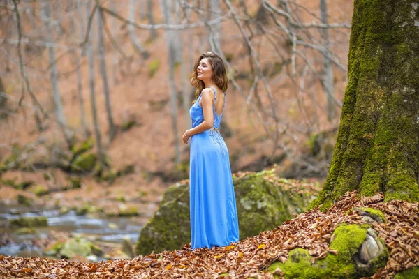 Mooie vrouw in blauwe jurk in het bos in de herfst dag — Stockfoto