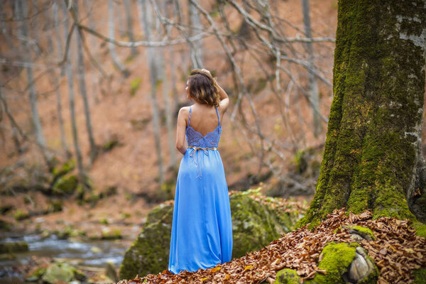 Beautiful woman in blue dress in the forest in autumn day
