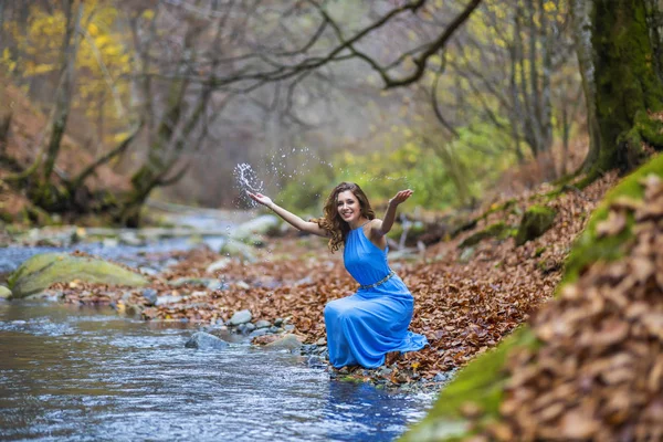 Mujer en vestido azul cerca de un río en el día de otoño — Foto de Stock