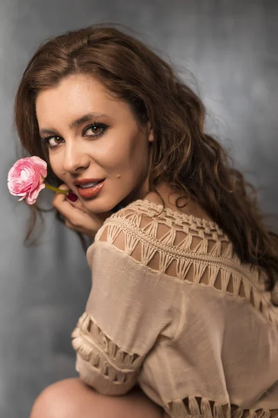 Portrait of young woman with beautiful professional makeup and flower on grey background