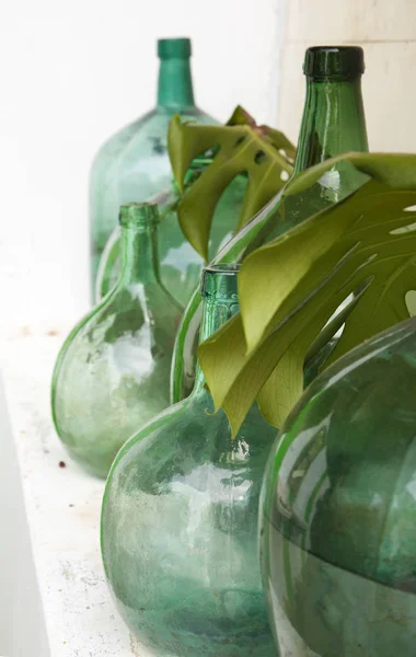 vintage garden decor - old glass containers and monstera leaves