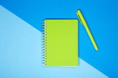 Yeşil defter ve kalem renkli bir arka plan üzerinde