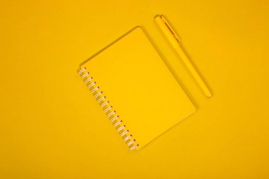 Sarı defter ve kalem sarı bir arka plan üzerinde