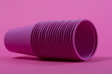 Pembe bir arka plan üzerinde plastik tek kullanımlık pembe su bardağı