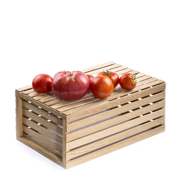 Pomodori maturi su una scatola di legno su uno sfondo bianco . — Foto Stock