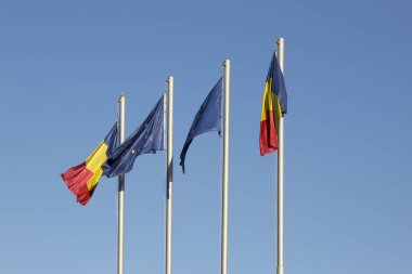 Romanya ve Avrupa Birliği mavi gökyüzüne karşı bayrakları taşıyan sokak bayrak direkleri.