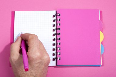 El ile üzerinden bir açık defter bir kalem