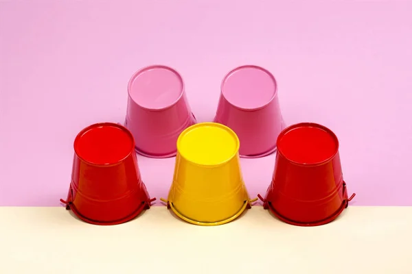 Rosa, röda och gula hinkar på en färgad bakgrund — Stockfoto