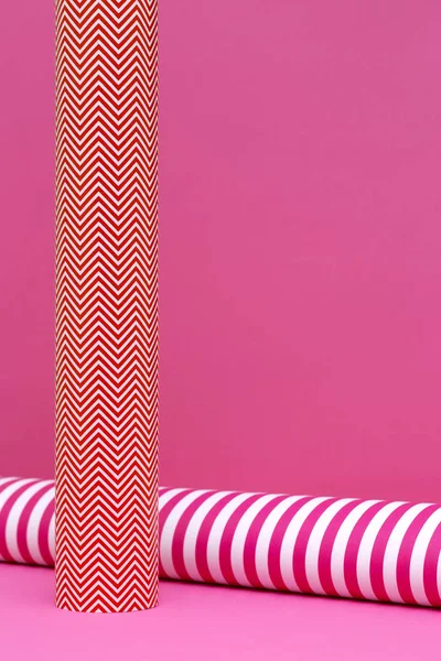 Paper rolls of colored paper on a pink background.