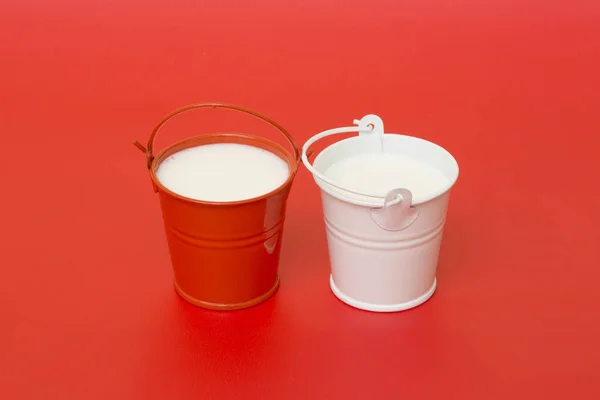 Rote Und Weiße Eimer Mit Milch Auf Rotem Grund — Stockfoto