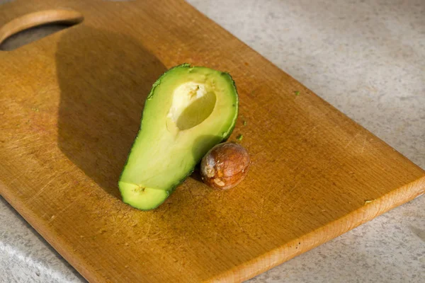 Cut avocado fruit with stone on kitchen board