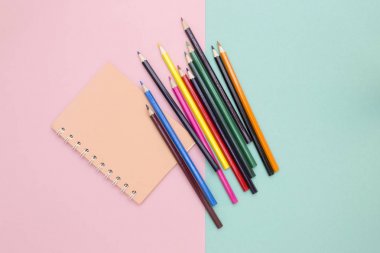Renkli kalemler ve renkli bir arka plan, üstten görünüm üstünde defter
