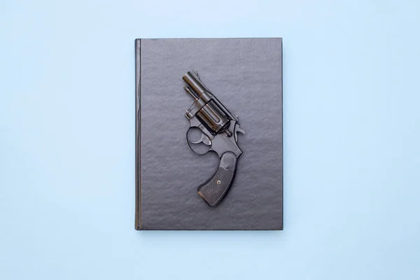 Libro y pistola sobre fondo azul —  Fotos de Stock