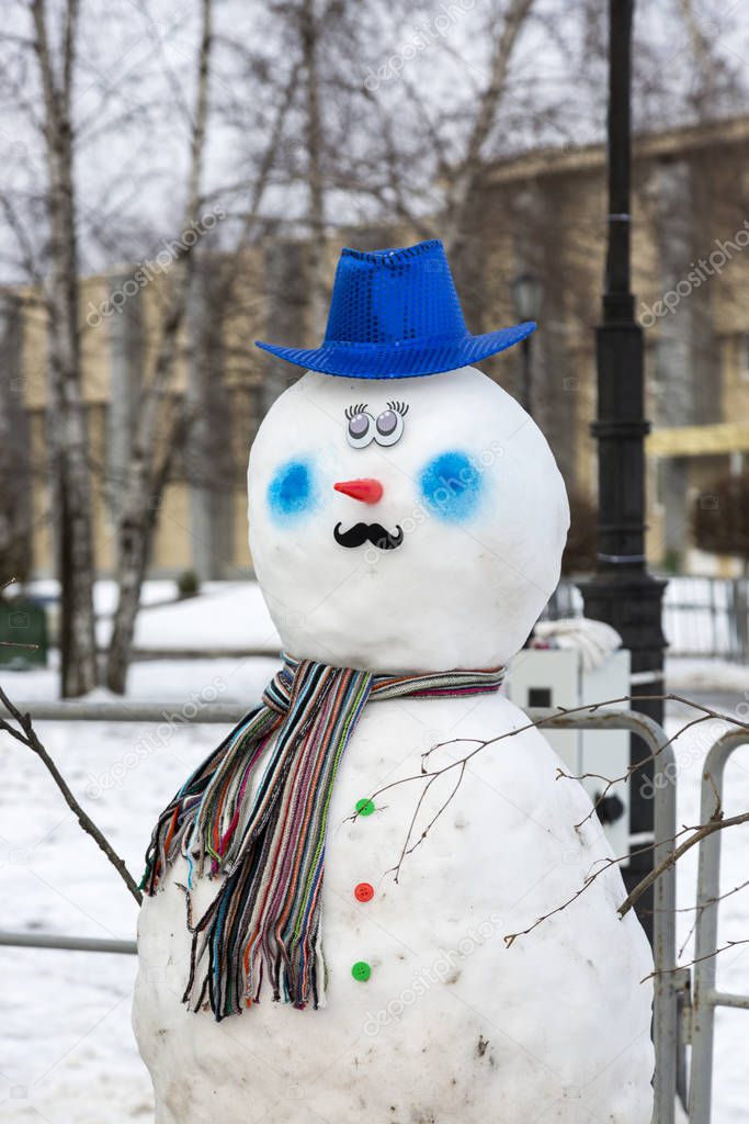 Head and torso of a decorated snowman on a winter street