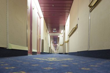 Modern yolcu feribotunun güvertesinde kabin kapıları olan uzun bir koridor.