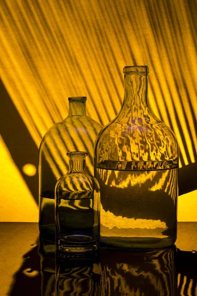 影のある黄色の背景にガラス瓶で静物画 — ストック写真