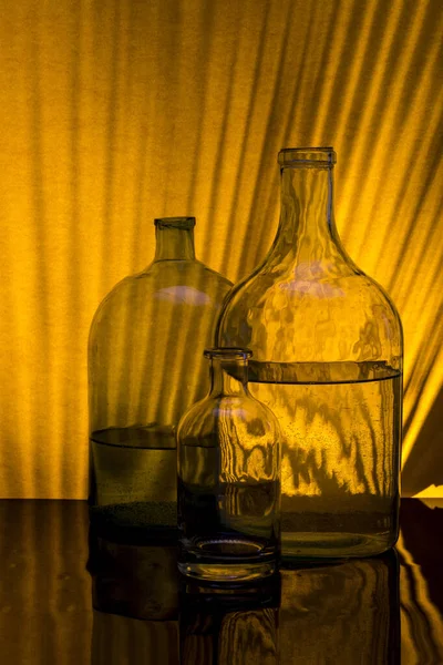 Still Life Glass Bottles Yellow Background Shadows — Stock Photo, Image