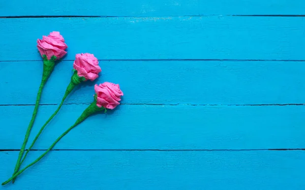 Fleurs de roses fraîches en rayon de lumière sur fond de bois peint turquoise. Concentration sélective. Place pour le texte . — Photo