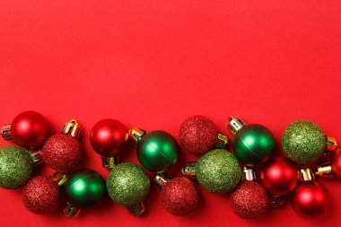 Noel tebrik kartı kompozisyonu. Kırmızı arka planda kırmızı ve yeşil toplar. Düz konum, üst görünüm, kopyalama alanı