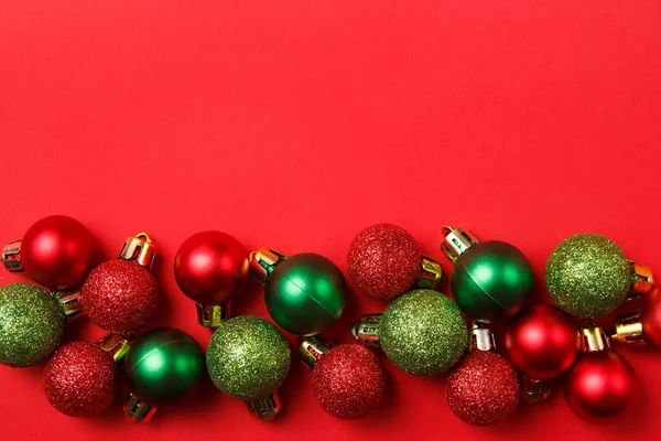 Christmas greating card composition. Christmas red and green balls decorations on red background. Flat lay, top view, copy space — ストック写真