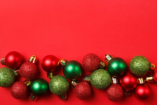 Skład kartki świątecznej. Boże Narodzenie czerwone i zielone kulki dekoracje na czerwonym tle. Płaskie ułożenie, widok z góry, przestrzeń do kopiowania Zdjęcie Stockowe