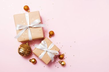 Noel tebrik kartı kompozisyonu. Pembe arka planda beyaz kurdeleli el işi kağıt hediye. Altın toplar ve konfeti yıldızı. Düz yatış, üst görünüm, moda tarzı.