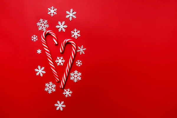 Composición navideña. Caramelo con copos de nieve sobre fondo rojo. Invierno, concepto de año nuevo. Plano, vista superior, espacio para copiar — Foto de Stock