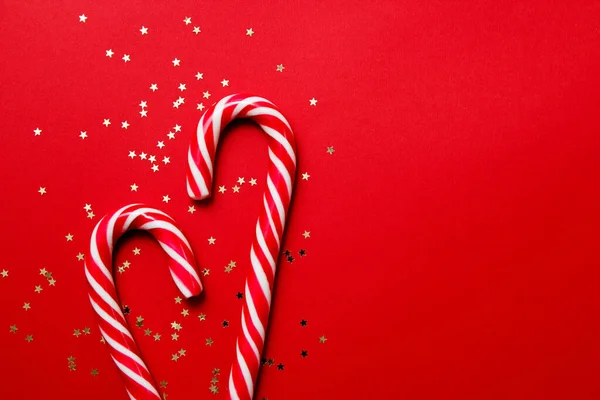 Composición navideña. Caramelo con confeti estrella sobre fondo rojo. Invierno, concepto de año nuevo. Plano, vista superior, espacio para copiar —  Fotos de Stock