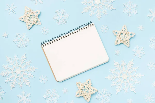 Cuaderno limpio para objetivos o lista de tiendas de Navidad y resoluciones sobre fondo azul con estrellas decorativas y copos de nieve. Vista superior, plano, espacio para copiar —  Fotos de Stock