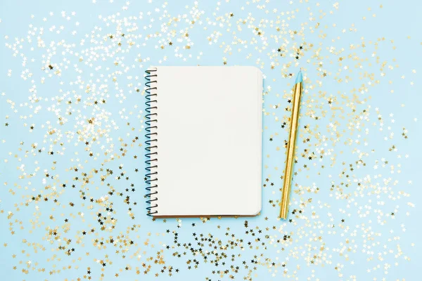 Schoon notitieboekje voor doelen of kerst winkel lijst en resoluties op blauwe achtergrond met gouden pen en confetti ster. Bovenaanzicht, flat lay, kopieerruimte — Stockfoto