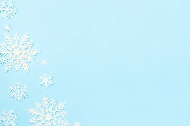 Noel ya da kış kompozisyonu. Mavi pastel arka planda kar taneleri süslemesi. Düz konum, üst görünüm, kopyalama alanı.