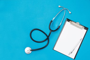 Mavi arka planda steteskoplu doktor reçetesi yazmak için boş kağıtların üst görüntüsü. Sağlık hizmeti konsepti. Üst görünüm, düz görünüm, kopyalama alanı.