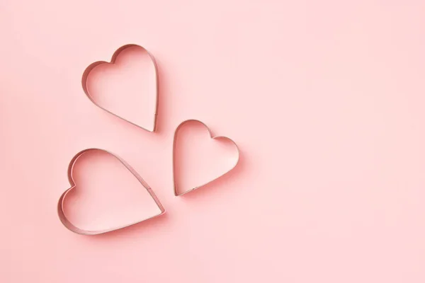 3 자르는 사람들은 분홍빛 배경에 하트 모양의 쿠키를 놓는다. 발렌타인 카드 콘셉트. 맨 위 뷰, 텍스트를 위한 복사 공간. — 스톡 사진