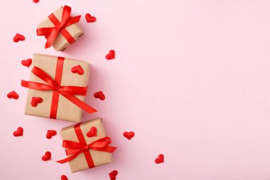 Pembe arka planda kırmızı pruva ve kalp konfetiyle hediyeler. Düz yatış stili. Sevgililer Günü konsepti