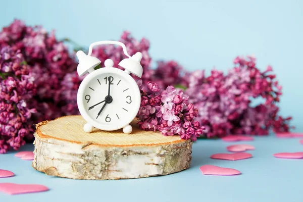 Lilac flowers with vintage tiny alarm clock on blue background. Spring time morning concept. — 스톡 사진