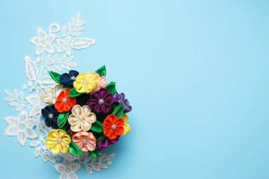 Mavi arka planda el yapımı saten çiçekler. Üst görünüm, düz görünüm, kopyalama alanı.